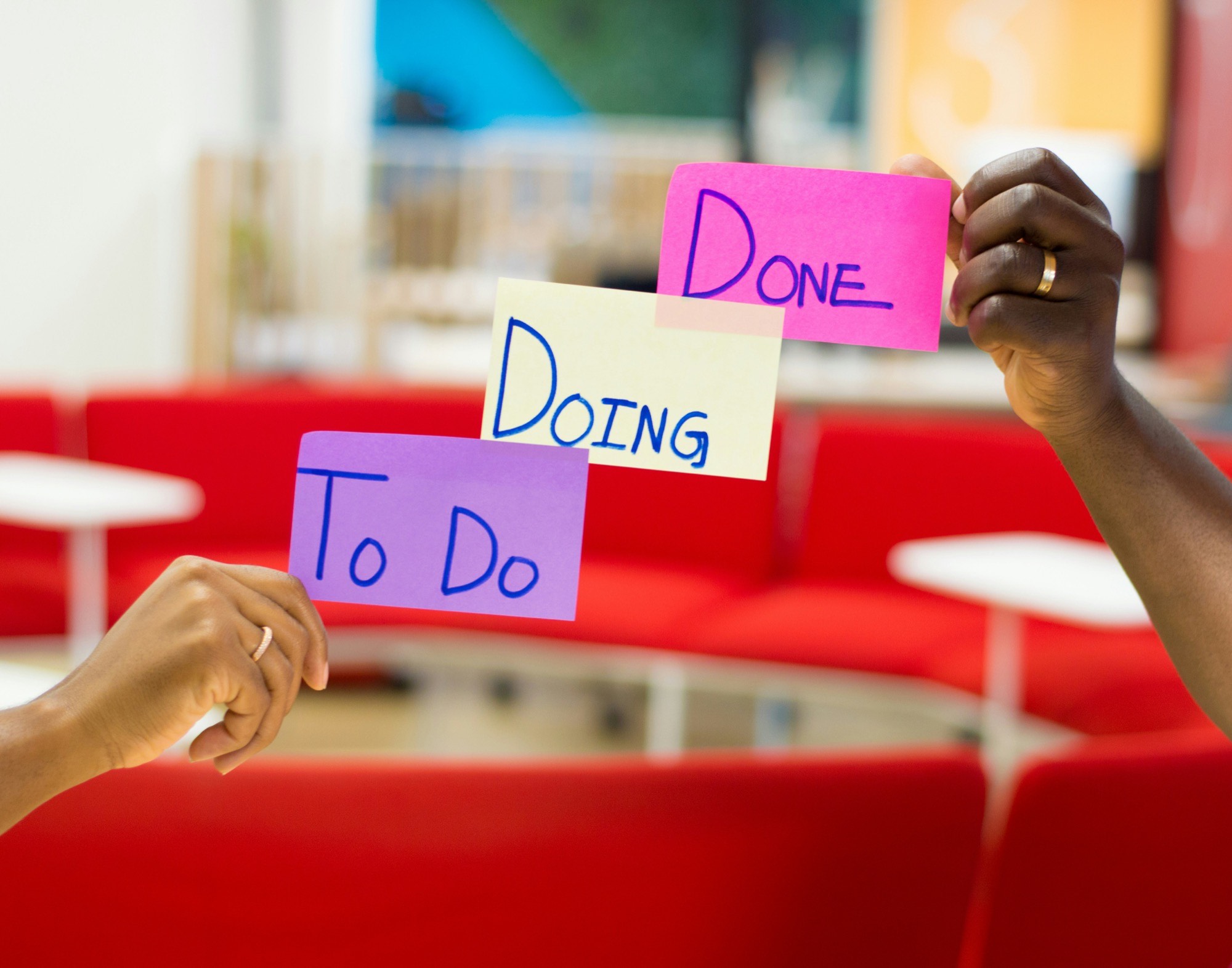 Hands holding To Do, Doing and Done sticky notes for project planning